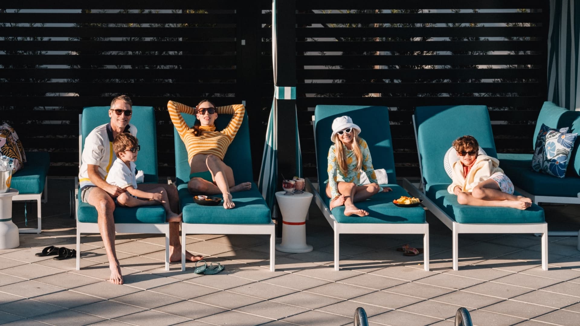 A family relaxes on teal lounge chairs inside a private poolside cabana at the resort.